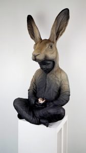 Hannes Verhoeven, "Slow Down," marble composite, 80 cm — child in a hare costume seated cross-legged holding a small gilded snail