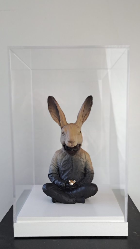 Hannes Verhoeven, "Slow Down in Bell Jar," marble composite in glass case, 33 cm — the seated hare-costume figure displayed under a bell jar