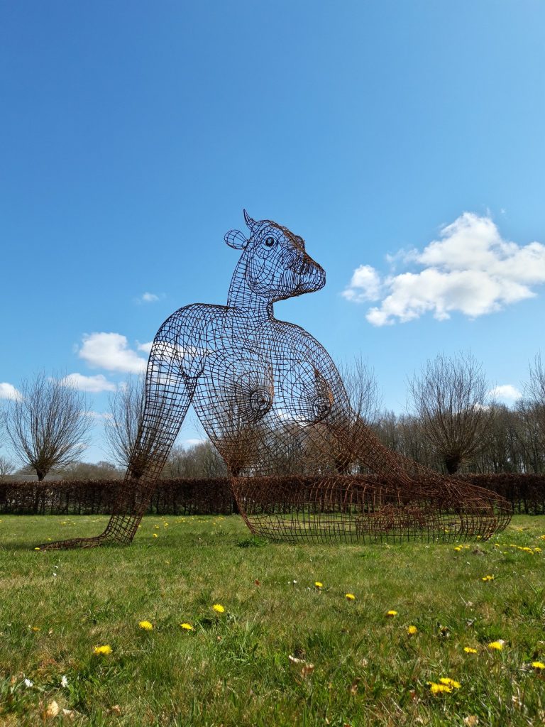 Hannes Verhoeven, "Cow Woman," steel, 300 cm — an outdoor wireframe sculpture of a reclining cow-woman figure
