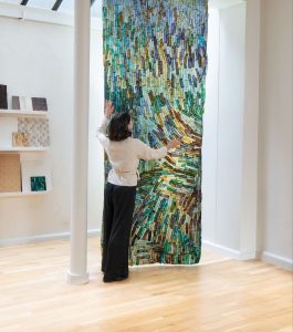 Loumi Le Floc'h, Precious Peels — large hanging panel of dyed eggplant skin in a studio, viewed by a visitor