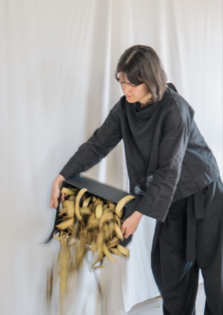 Loumi Le Floc'h pouring dried, processed eggplant skins from a box in her studio